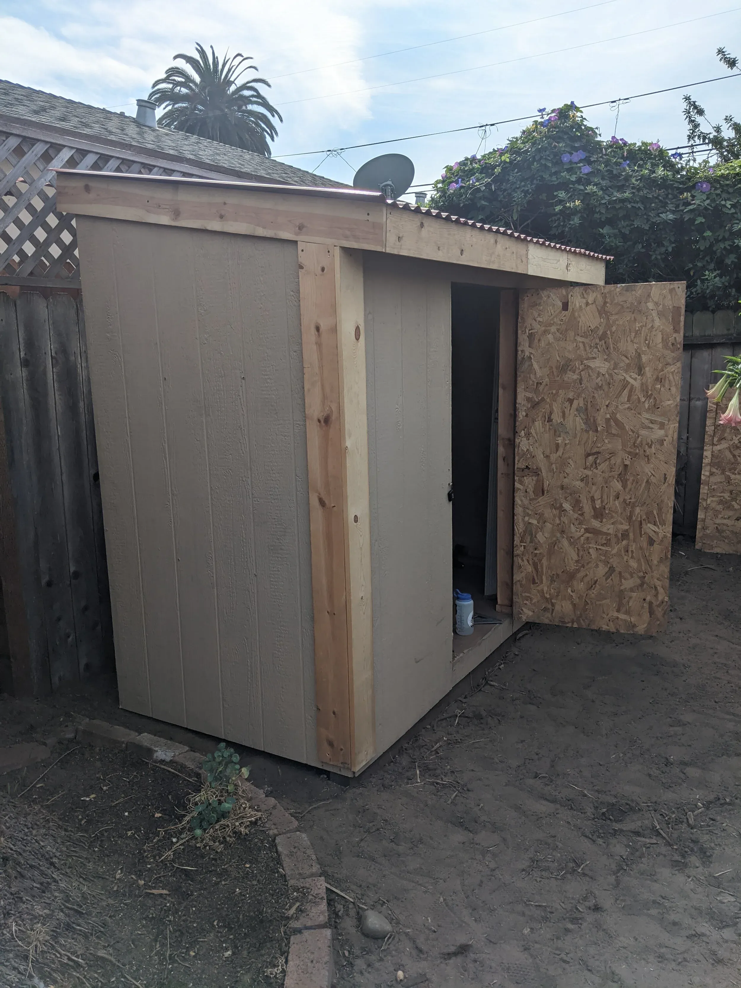 At this point I had the front corner trim installed. Also note the door, which was built from scrap: two sheets of OSB plywood attached to a simple 2 x 4 frame.